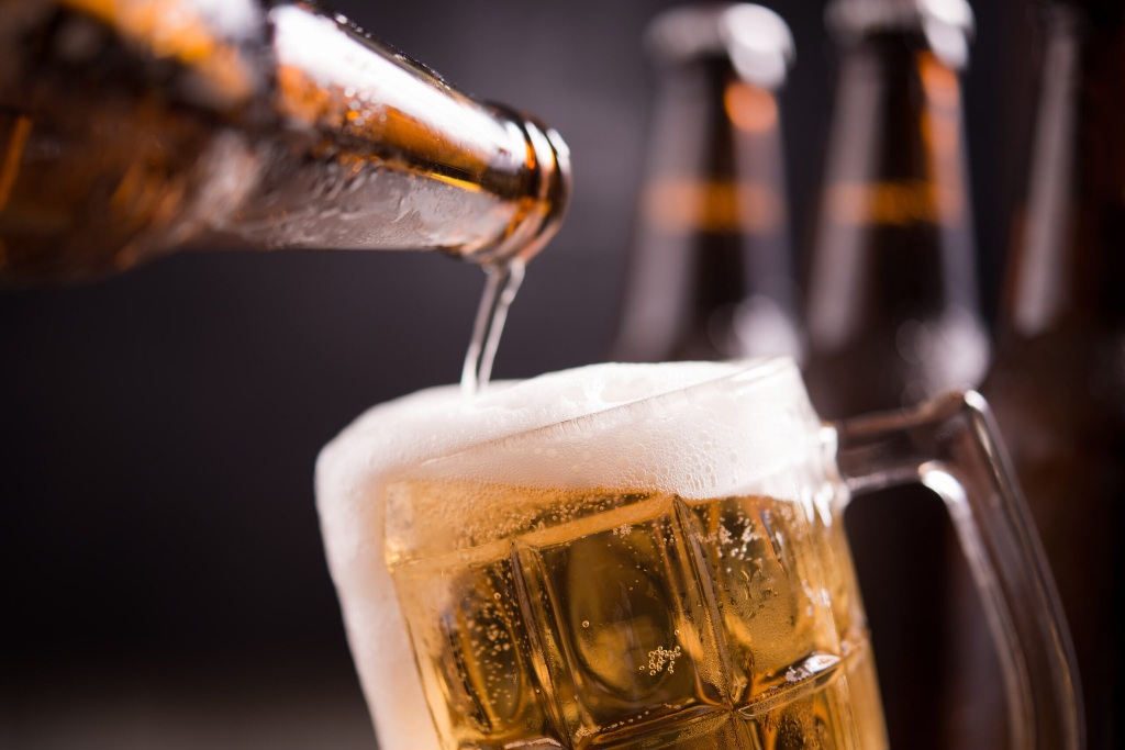 glass-bottles-of-beer-with-glass-and-ice-on-dark-background-1-min-scaled